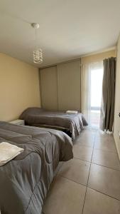 a bedroom with three beds and a window and a tile floor at Departamento frente al Arena Maipú Mendoza in Maipú