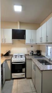 a kitchen with white cabinets and a stove and a sink at Departamento frente al Arena Maipú Mendoza in Maipú