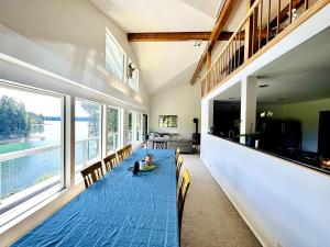 een kamer met een lange tafel met stoelen en ramen bij Waterfront Escape - Dock, Hot Tub, Theater in Grapeview