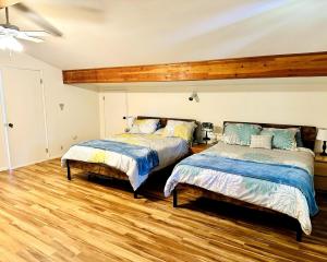 twee bedden in een kamer met houten vloeren bij Waterfront Escape - Dock, Hot Tub, Theater in Grapeview