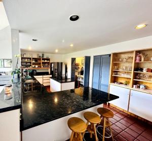 een keuken met een zwart aanrecht en houten krukken bij Waterfront Escape - Dock, Hot Tub, Theater in Grapeview