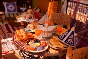 una mesa con una bandeja de alimentos para el desayuno y zumo de naranja en Riad Lalla Marrakech, en Marrakech