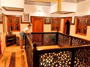 Una mujer parada sobre una barandilla en una casa en Riad Lalla Marrakech, en Marrakech