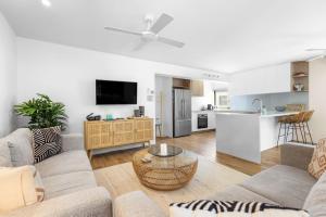 Una sala de estar con dos sofás y una cocina. en 7 28 Viewland Drive Noosa Heads, en Noosa Heads