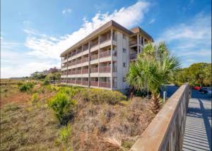 an apartment building on a hill with a boardwalk at Direct Luxury Oceanfront - On The Beach! Amazing Sunrises, 2 Pools & Bar! in Hilton Head Island
