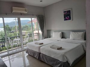 a bedroom with a large bed and a balcony at Rose Villa Hote in Pak Chong