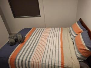 a bed with a striped comforter with two batteries on it at Holly's Flat Close to Ferry And EV in Wellington