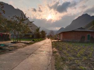 Làng CacにあるDuong Thuong - Eco Houseの山を背景にした建物へと続く未舗装道路