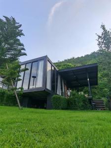Una casa de cristal en un césped con un árbol. en Nara Black Mountain, en Ban Tha Chang