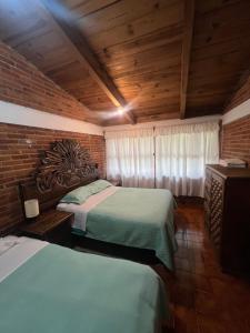 Un dormitorio con dos camas y techo de madera. en Cabaña cerca del Santuario Valle de Bravo, en Valle de Bravo