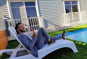 a man sitting in a chair on the lawn at שלוות יעקב in Sifsufa