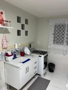 a white kitchen with a stove and a sink at Apto Elegante no Vieiralves in Manaus +1 photo
