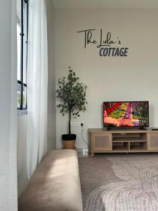 a living room with a tv and a potted plant at The LuLas Cottage in Malacca
