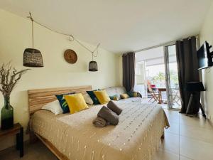 sypialnia z łóżkiem z żółtymi i niebieskimi poduszkami w obiekcie Studio Cocooning Diamond - Piscine et Terrasse vue mer w mieście Le Diamant