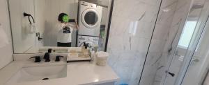 a woman taking a picture of a bathroom with a washing machine at Sea view stay in Lantzville