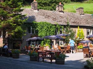 a restaurant with tables and umbrellas in front of a building at The Lamb Inn in Chinley