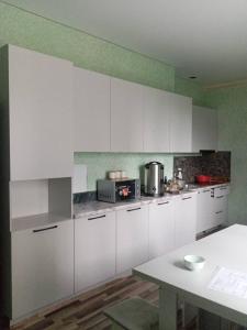a kitchen with white cabinets and a table in it at Хостел Асыл-Таш in Bishkek