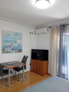 sypialnia z biurkiem, stołem i telewizorem w obiekcie Apartment House Nono w mieście Povljana