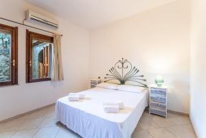 a white bedroom with a bed and a window at Premium Villa Eleonora, 250m to beach in Fort Village