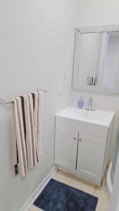 een witte badkamer met een wastafel en een spiegel bij Beautiful Studio with Patio in Mississauga in Mississauga