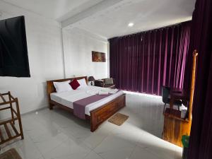 una camera da letto con un letto e una finestra con tende viola di Ciel Star Anuradhapura a Anuradhapura