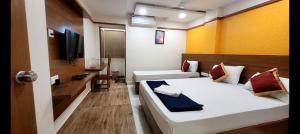 a hotel room with two beds and a television at Alfouz Guest House in Chennai