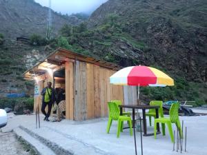 a man standing outside of a small building with a table and an umbrella at Hotel Chandrlok in Madheso