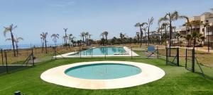 an empty swimming pool with palm trees and the ocean at Niza Playa in Almayate Alto