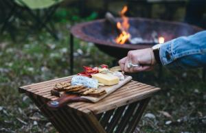 une personne tenant une assiette de fromage et des craquelins à côté d'un gril dans l'établissement Bombah Point Eco Cottages, à Bulahdelah 22 autres photos