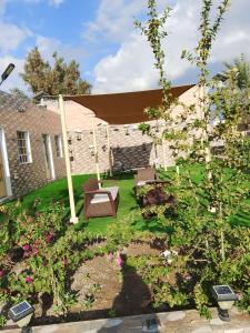 Green Resort Hotel AL khaburah في As Sarhāt: حديقة فيها مقعد ومظلة