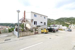 a white building with cars parked in a parking lot at Apartmani Vini in Hvar