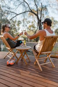 Ein Mann und eine Frau sitzen auf Stühlen und trinken Wein. in der Unterkunft Moodemere Lake House in Rutherglen