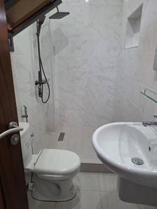 a white bathroom with a toilet and a sink at Villa Hélène in Nianing +2 photos