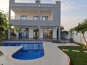 a house with a swimming pool in front of it at Villa Hélène in Nianing