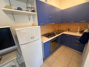 a kitchen with blue cabinets and a white refrigerator at Residence Patty in Caorle