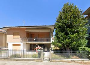 a house with a fence in front of a tree at Appartamento mare in Cesenatico