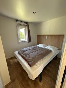 a large bed in a bedroom with a window at Camping les Marguerites in Gamaches