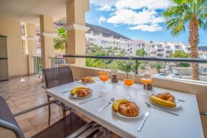 a table with food and glasses of orange juice on a balcony at Castle Harbour with heated pool ap Patricia in Los Cristianos