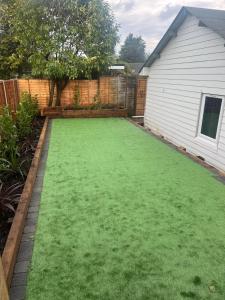 a yard with green grass next to a house at Adorable Self Contained detached annexe in Holmwood