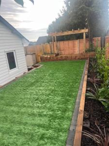 a backyard with green grass and a wooden fence at Adorable Self Contained detached annexe in Holmwood