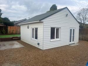 a small white shed with two windows in a yard at Adorable Self Contained detached annexe in Holmwood