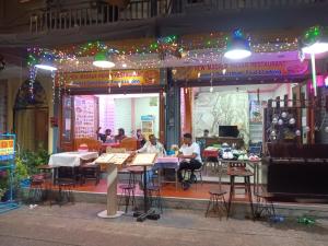 a group of people sitting at tables in front of a restaurant at New Masala Indian restaurant in Bangkok