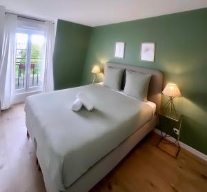 a bedroom with a large white bed with green walls at Outstanding Apartment-Near Disneyland Paris in Chessy