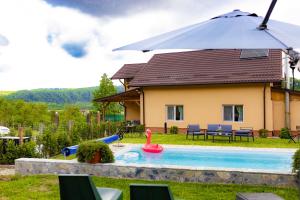 a house with a swimming pool with an umbrella at David House Piscina incalzita si jacuzzi in Pietrari
