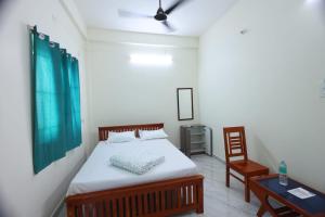 a bedroom with a bed and a table and a chair at SSN Residency in Tiruvannāmalai