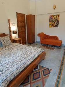 een slaapkamer met een bed en een bank bij the Kutumb- Where the Himalayas come alive! in Pālampur