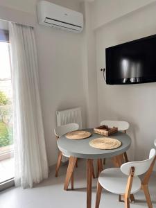 jadalnia ze stołem i krzesłami oraz telewizorem w obiekcie Fays luxury apartments by the sea w mieście Finikounda
