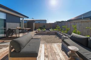 a patio with a couch on a wooden deck at Mana Nalu - Mapua Holiday Home in Mapua
