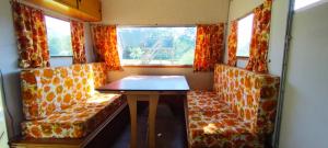 a small room with a table and chairs in a train at Caravane vintage in Camoël