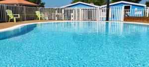 a blue swimming pool with two chairs and a fence at Caravane vintage in Camoël +12 photos